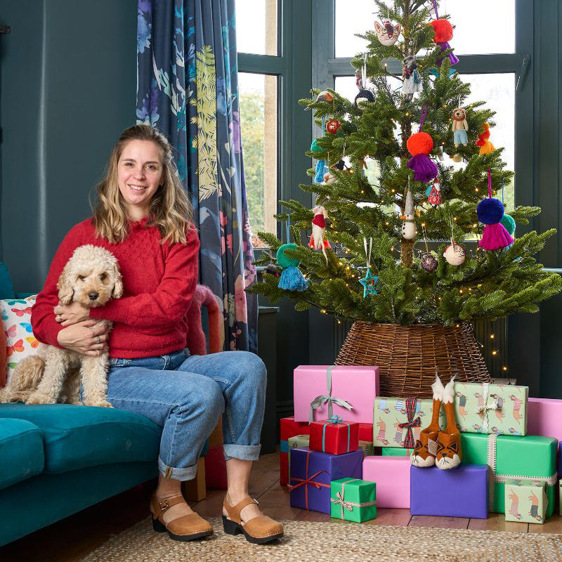 Mary Kilvert with Honey the dog, sitting next to a Christmas tree in her home